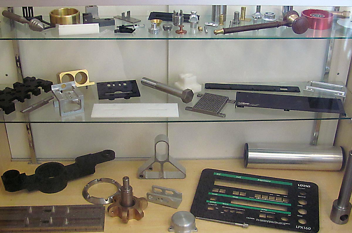 Glass shelf displaying parts milled and turned by Candlewood Tool and Machine Shop